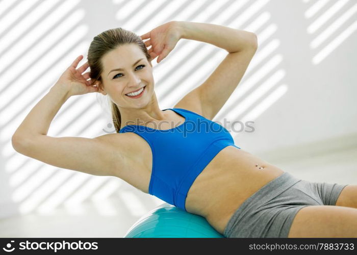 photo of attractive smiling woman doing workout with a gym ball