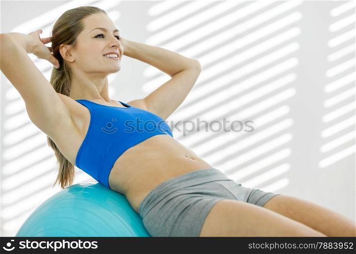 photo of attractive smiling woman doing workout with a gym ball