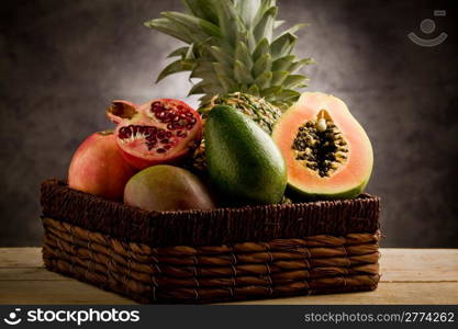 photo of basket full with delicious tropical fruits in front of a rural background