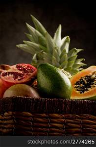 photo of basket full with delicious tropical fruits in front of a rural background