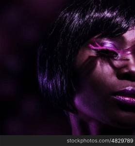 Photo of beautiful black woman with fashionable pink eyelashes isolated on dark background, half face, stylish makeup, female with gorgeous short haircut, luxury beauty salon, vogue concept