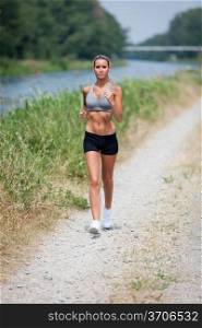 Photo of beautiful blonde woman running along the riverside