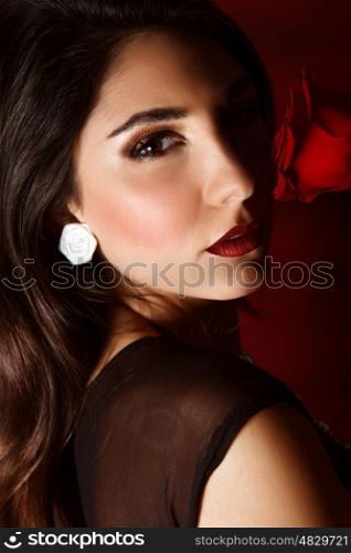 Photo of beautiful brunette woman with red rose isolated on dark background, closeup portrait of gorgeous female with perfect makeup, luxury beauty salon, Valentine day, passion and elegance concept