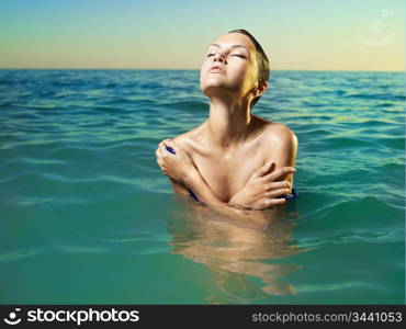 Photo of beautiful elegant woman in the sea at sunset