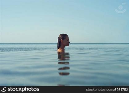 Photo of beautiful elegant woman in the sea at sunset