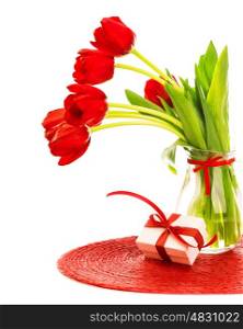 Photo of beautiful red fresh tulips flowers in glass vase, white gift box with red ribbon bow on the table in studio, romantic still life isolated on white background, happy mothers day, love concept