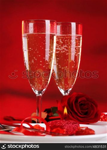Photo of beautiful Valentine day dinner still life, two glasses for champagne, alcohol beverage, romantic drink, sparkling wine, red rose and candle, festive table setting, love concept