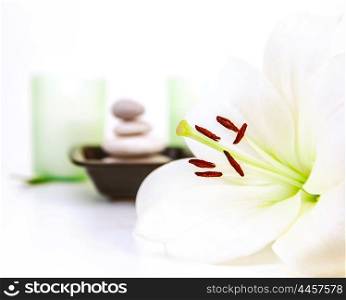 Photo of beautiful white lily flower, pebble stones, two candles, spa still life, dayspa, luxury beauty salon, hygiene items, bath objects, healthy lifestyle, organic cosmetics, resort concept&#xA;