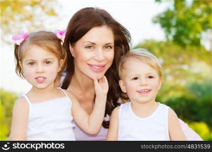Photo of beautiful woman with two cute kids, closeup portrait of young mother with sweet daughter and lovely son outdoors, adorable children with mommy on the park in spring, happy family concept
