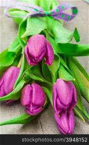 Photo of bouquet of violet tulips over wooden table