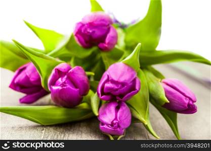 Photo of bouquet of violet tulips over wooden table