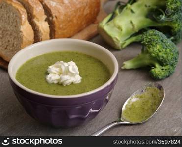 Photo of broccoli soup with a loaf of bread in the background.&#xA;