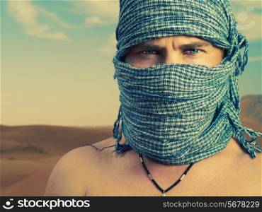 Photo of brutal man in Bedouin scarf in desert