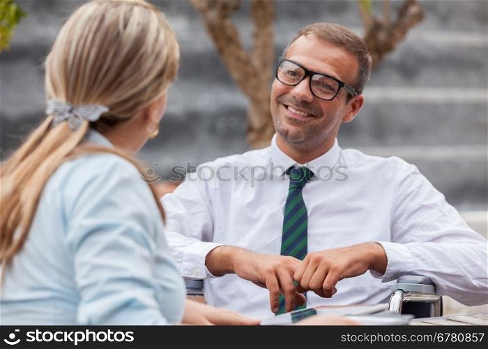Photo of businessman on wheelchair talks to his colleague