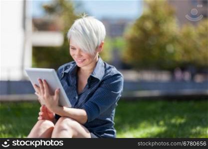 Photo of businesswoman outside in a park with tablet pc