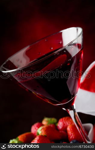 photo of calyx with cocktail with berries on red lighted backgroud