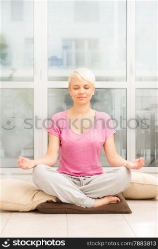 photo of caucasian blonde woman doing meditation on the floor at home