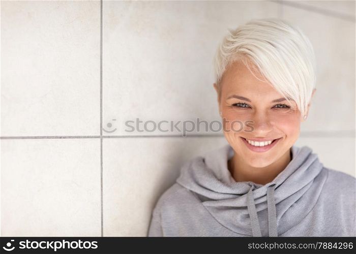 Photo of caucasian blonde woman standing next to a wall