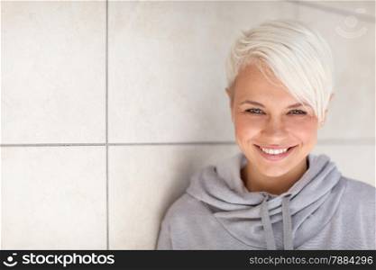 Photo of caucasian blonde woman standing next to a wall
