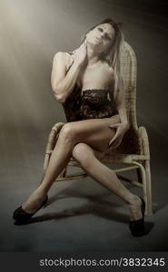 Photo of caucasian blonde woman with black lingerie posing on a chair