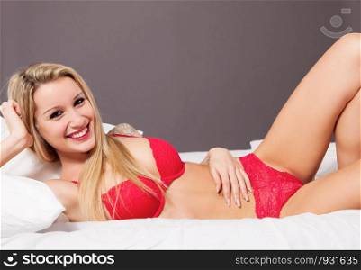 Photo of caucasian blonde woman with red lingerie in the bed