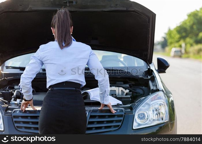Photo of caucasian businesswoman looking inside the car hood