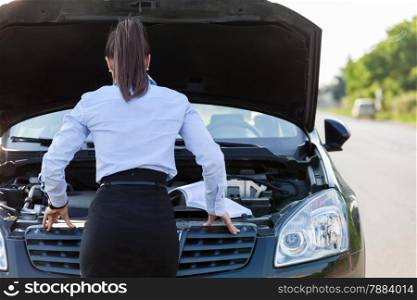 Photo of caucasian businesswoman looking inside the car hood