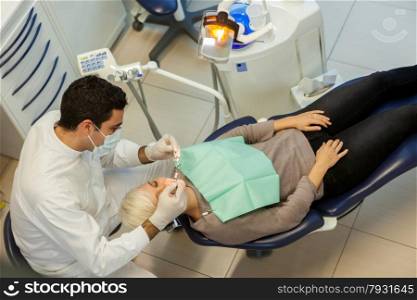 photo of caucasian dentist doing his job on a young blonde woman
