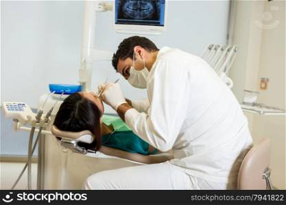 photo of caucasian male dentist visiting his young asian female patient in a dentist office