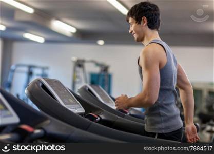 Photo of caucasian trained man running on a treadmill in the fitness studio