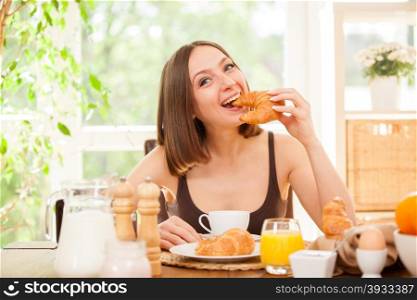 Photo of caucasian woman giving a bite to her croissant