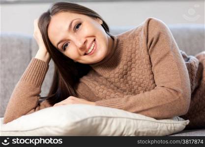 photo of caucasian woman lying on the couch and hugging the pillow