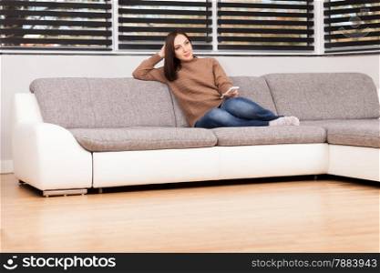 photo of caucasian young woman sitting on a sofa while looking tv