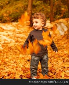 Photo of cheerful small kid having fun outdoors, adorable toddler play game on backyard, nice curly little boy enjoying walk in autumn park, beautiful autumn season, happy childhood&#xA;&#xA;