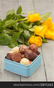 Photo of chocolate pralines with flowers over wooden table