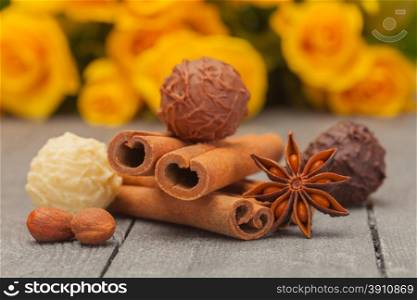 Photo of cinnamon sticks, star anise and chocolate truffles over wooden table
