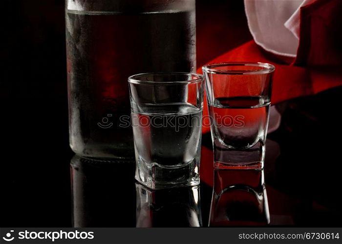 photo of cold vodka bottle with glass on black glass table