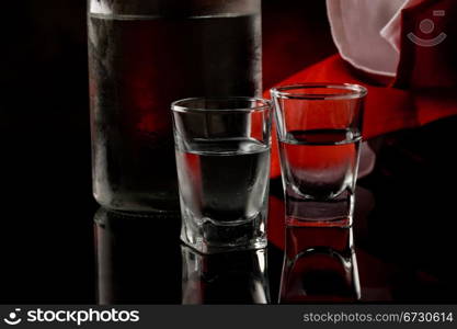 photo of cold vodka bottle with glass on black glass table