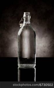 photo of cold water bottle on black glass table with reflection
