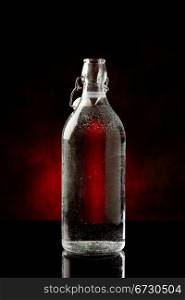 photo of cold water bottle on black glass table with reflection