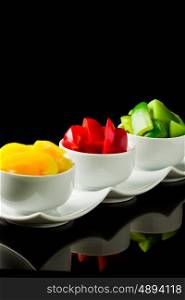 photo of colorful pepper inside three small bowls on black isolated background