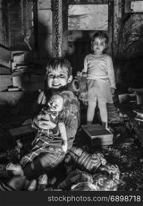 Photo of creepy young children standing over old dolls and in a barn covered in spiderwebs and dust.