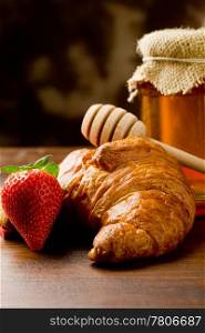 photo of croissants with honey and strawberries on wooden table