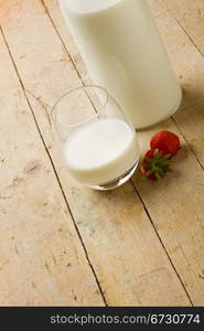 photo of cup of milk with strawberry on wooden table