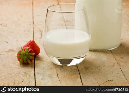 photo of cup of milk with strawberry on wooden table