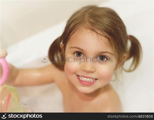 Photo of cute baby girl taking bath, happy childhood, child's hygiene, healthy adorable kid, sweet infant in bathroom, pretty toddler having fun in bathtub, baby's soap and shampoo, healthcare concept