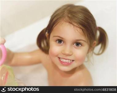 Photo of cute baby girl taking bath, happy childhood, child's hygiene, healthy adorable kid, sweet infant in bathroom, pretty toddler having fun in bathtub, baby's soap and shampoo, healthcare concept