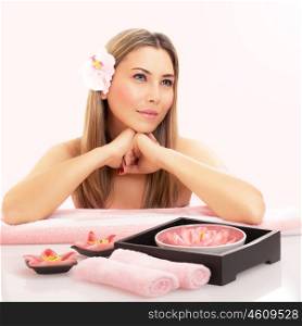 Photo of cute blond girl enjoying dayspa, sensual woman with orchid flower in hair sitting near massage table in spa salon, luxury beauty treatment, natural cosmetics, healthy lifestyle&#xA;