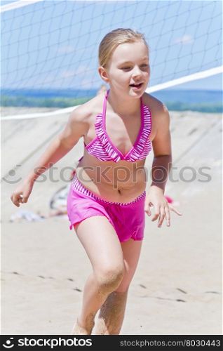 Photo of cute girl in pink swimsuit running on a beach