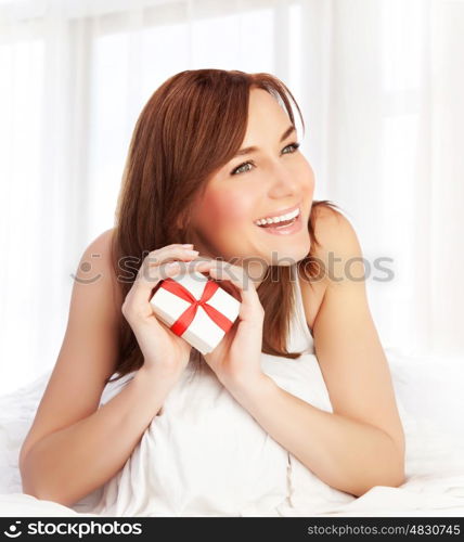 Photo of cute woman enjoying gift, closeup portrait of pretty female at home holding in hands little white present box with red ribbon, Valentine day, romantic holiday, love concept